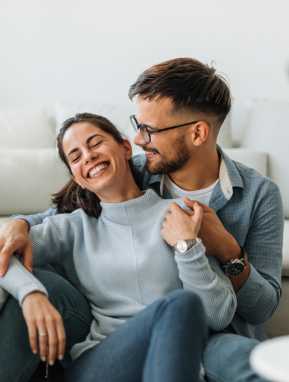 Man and woman laughing together at home after visiting a Stratford dental office