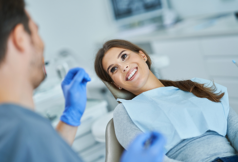 Woman in the treatment chair smiling at her dentist