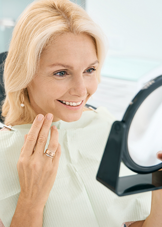 Woman in the dental chair admiring her smile in a mirror