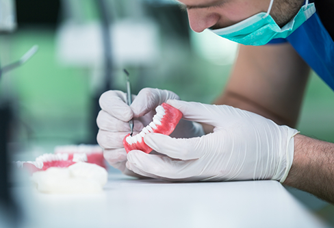 Dental professional closely adjusting a denture