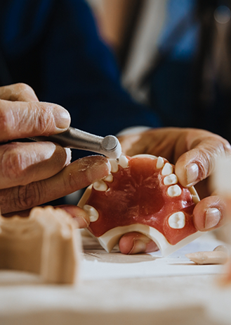 Dental lab worker adjusting a denture