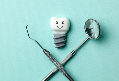 Illustration of a smiling dental implant next to a dental mirror and scaler