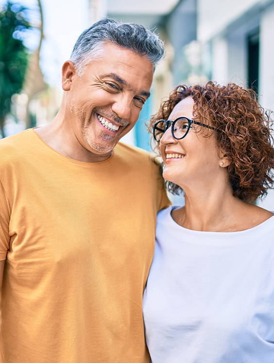 Man and woman smiling on a city sidewalk after cosmetic dentistry in Stratford