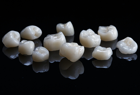 Several tooth colored dental crowns against a black background