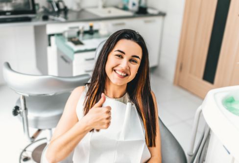 Smiling woman giving a thumbs up in the dental chair