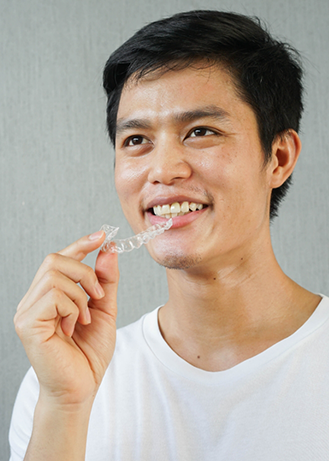 Man holding an Invisalign tray near his smile