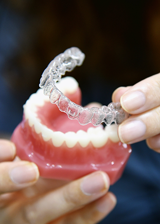 Dentist placing an Invisalign aligner over a model of an arch of teeth