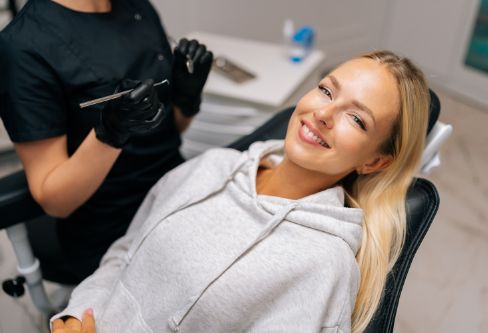 Smiling blonde woman leaning back in the dental chair