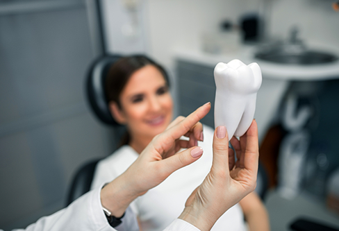 Dentist showing a model of a tooth to a patient in the treatment chair